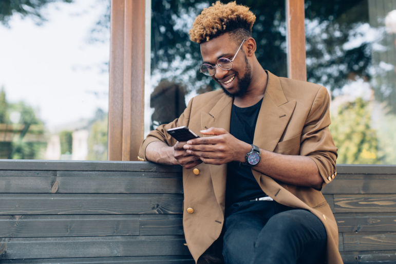 man texting on phone while smiling