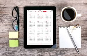 tablet and notepad with calendar for scheduling
